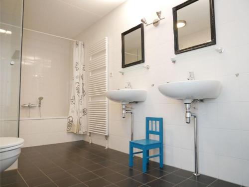 baño con 2 lavabos y silla azul en Het Strandleven 4, en Goote Keeten