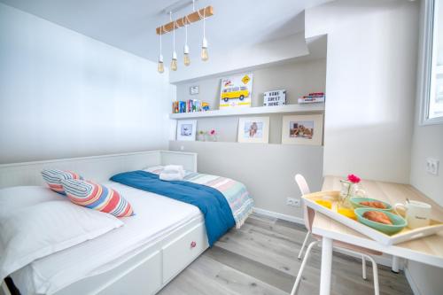 een kleine witte slaapkamer met een bed en een tafel bij Face à la mer - Première conciergerie in Palavas-les-Flots
