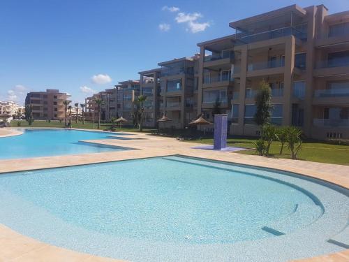 a large swimming pool in front of a building at Cozy & Luxurious apartment with seaview in Bouznika