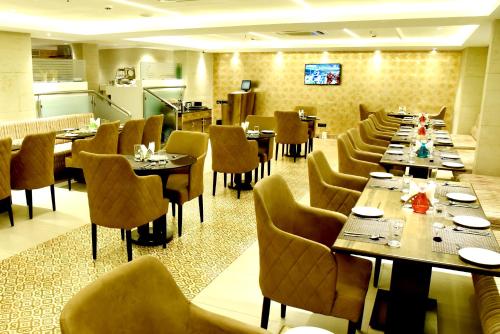 a restaurant with long tables and chairs and a kitchen at Royalton Hyderabad Abids in Hyderabad