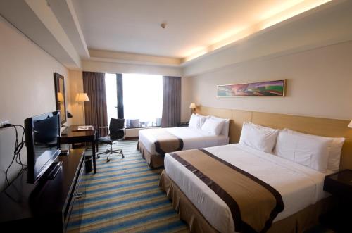 a hotel room with two beds and a television at Luxent Hotel in Manila
