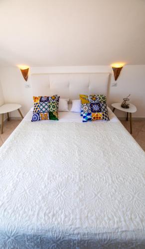 a large white bed with colorful pillows on it at Madonna della Scala in Castellabate