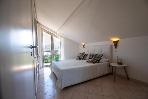 a white bedroom with a bed and a window at Madonna della Scala in Castellabate