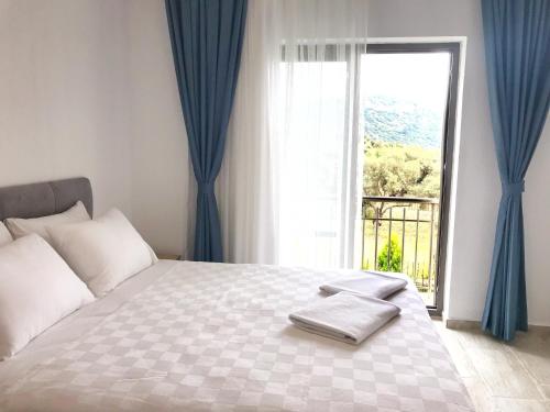 a bedroom with a bed with blue curtains and a window at Oliva Casa Apart Hotel in Datca