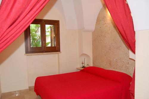una camera con letto rosso e finestra di La Stele di Rekale a Scauri