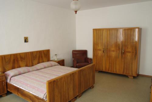 a bedroom with a bed and a cabinet and a chair at Da Francesca in Fiera di Primiero