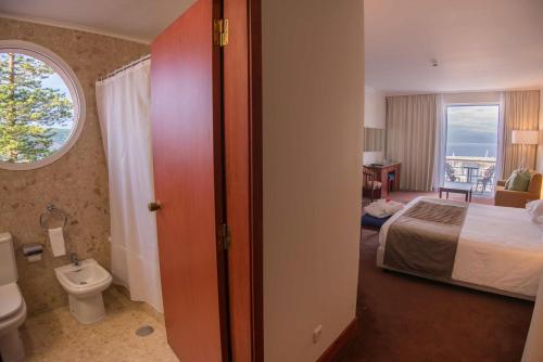 a hotel room with a bed and a toilet at Azoris Faial Garden – Resort Hotel in Horta