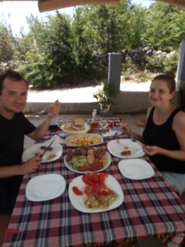 two people sitting at a table with plates of food at Apartments Nino Skadar lake in Virpazar