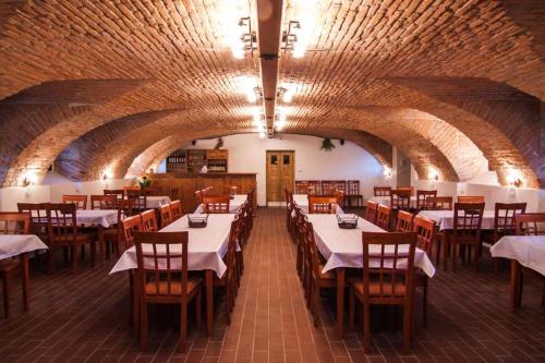 Hotel Pod Sluncem في Třebíz: غرفة طعام بطاولات بيضاء وكراسي خشبية