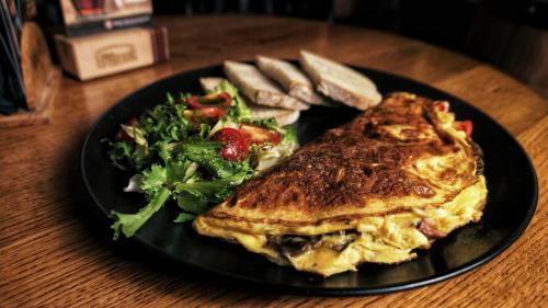 ein schwarzer Teller mit Essen, einem Sandwich und einem Salat in der Unterkunft Lord Jack Apartments in Rzeszów
