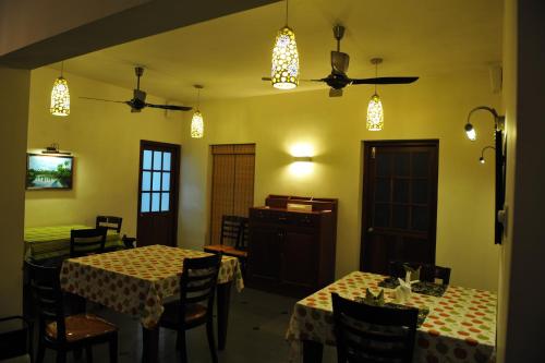 a dining room with two tables and chairs and lights at The Villa Romantica in Nedumbassery