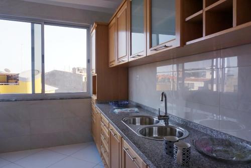 a kitchen with a sink and a large window at AL Guesthouse in Praia