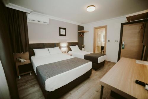 a hotel room with two beds and a table at Helen Hotel in Çanakkale