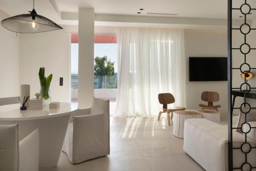 Glyfada South42 في أثينا: غرفة معيشة بيضاء مع طاولة وكراسي بيضاء