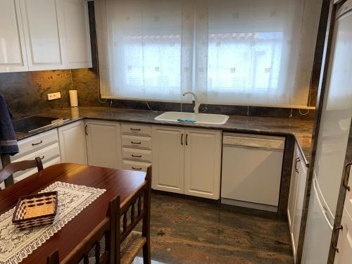 a kitchen with white cabinets and a wooden table at Cala Tere 2on pis in Cadaqués