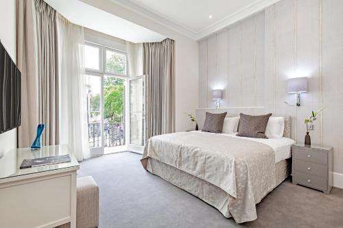 a white bedroom with a bed and a large window at Chesham Court Knightsbridge in London