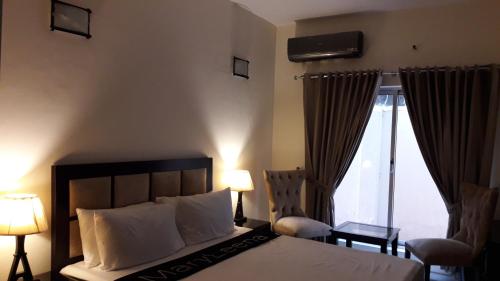 a bedroom with a bed and two chairs and a window at MaryLeena Hotel Gulberg in Gulberg