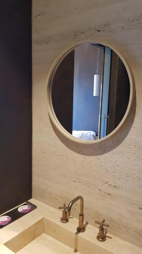 a bathroom sink with a round mirror above it at Al Faya Retreat by Sharjah Collection in Sharjah