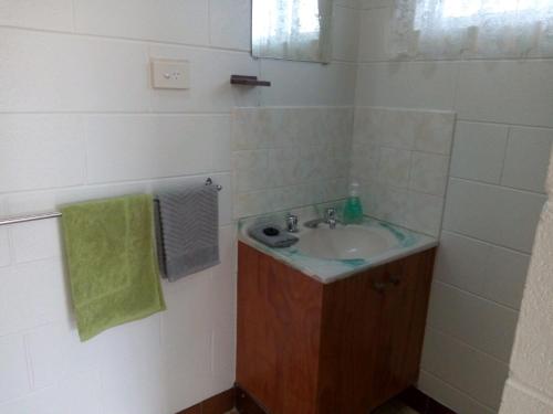 a bathroom with a sink and a green towel at Anchor In Holiday Units South Mission Beach in South Mission Beach