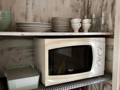 a microwave on a shelf with plates and bowls at Pensionat Gyllenhjelmsgatan in Strängnäs