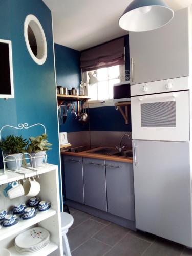 Il comprend une cuisine dotée de murs bleus et d'un réfrigérateur blanc. dans l'établissement Les cigognes, à Bagnoles-de-l'Orne