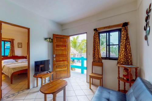a living room with a bed and a tv and a bedroom at Mayan Falls in Caye Caulker
