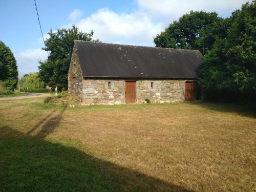 an old stone barn with a black roof in a field at Le Botcol in Plouguernével