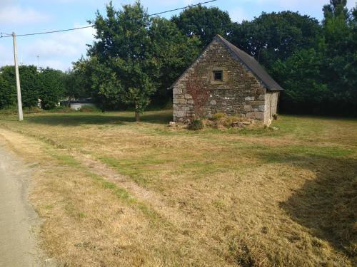 an old stone barn in a field next to a road at Le Botcol in Plouguernével