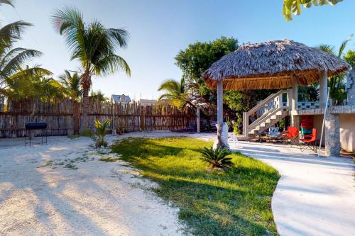 a house with a straw umbrella and a yard at Mayan Falls in Caye Caulker