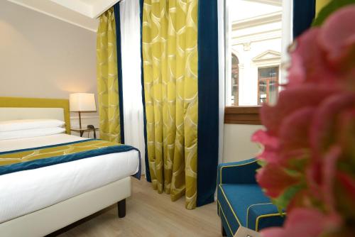 a bedroom with a bed and a window and a chair at Hotel Canon d'Oro in Conegliano
