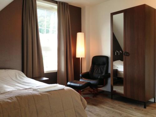 una camera d'albergo con letto, sedia e specchio di Torget Hotell a Måløy