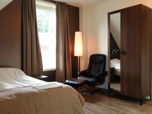 a hotel room with a bed and a chair and a mirror at Torget Hotell in Måløy