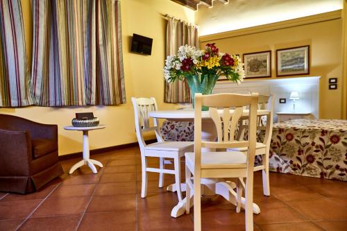 a dining room with a table with chairs and a vase of flowers at Albergo Trattoria Il Leone in Pomponesco