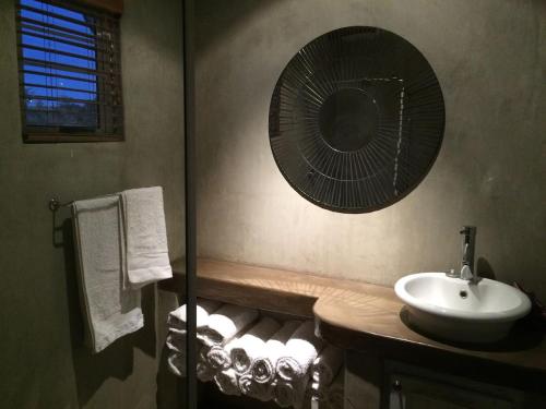 ein Bad mit einem Waschbecken und einem Ventilator an der Wand in der Unterkunft Kalahari Cottage in Askham