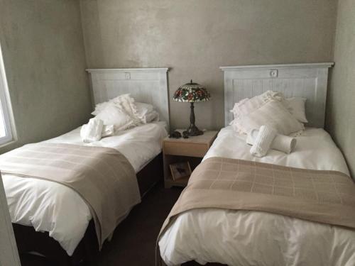 dos camas sentadas una al lado de la otra en un dormitorio en Kalahari Cottage, en Askham