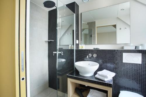 a bathroom with a sink and a glass shower at Hotel Auguste in Paris