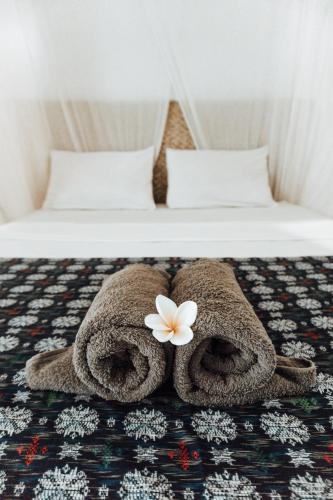 a bed with towels and a flower on it at Balangan Inn Surf Homestay in Jimbaran
