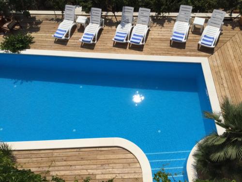 a swimming pool with lounge chairs and a group oficans at Luigi apartments in Dubrovnik