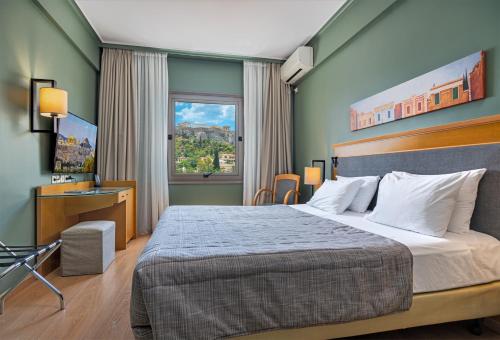 Schlafzimmer mit einem Bett, einem Schreibtisch und einem Fenster in der Unterkunft Plaka Hotel in Athen