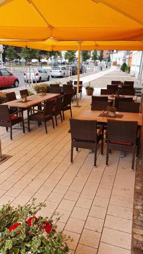 a restaurant with tables and chairs and a yellow umbrella at Hotel Stadt Magdeburg in Perleberg