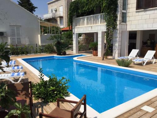 a swimming pool with chairs next to a building at Luigi apartments in Dubrovnik