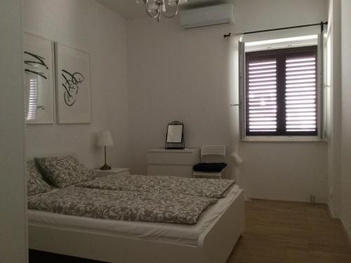 a white bedroom with a bed and a window at Luigi apartments in Dubrovnik