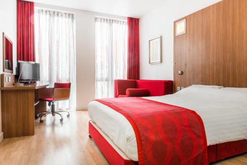 a hotel room with a bed and a desk and a television at Ramada Encore Leicester City Centre in Leicester
