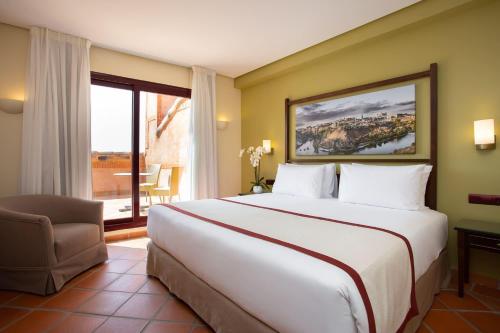 a hotel room with a large bed and a window at Exe Layos Golf in Layos