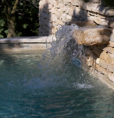 une personne est dans l'eau dans une piscine dans l'établissement Le Moulin des Sources, à Gordes