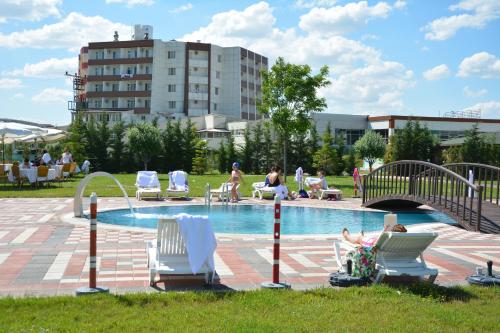 a group of people sitting in chairs by a pool at GARDEN KALE THERMAL HOTEL in Afyon