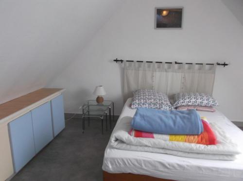 Un dormitorio con una cama con almohadas y una mesa. en villa le patio, en Saint-Pair-sur-Mer