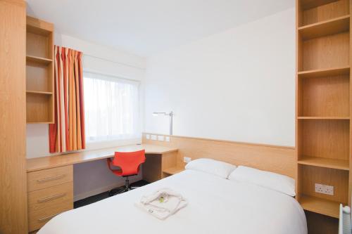 a bedroom with a bed and a desk and a red chair at Venue Reading Accommodation in Reading