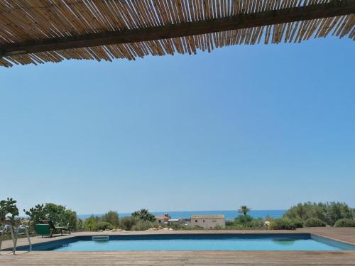 a view of a swimming pool with a thatched roof at CASADORATA buen retiro vista mare in Donnalucata
