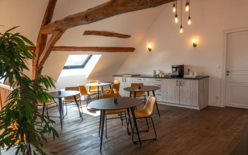 Una habitación con mesas y sillas y una cocina. en La Maison de Souhey, en Souhey
